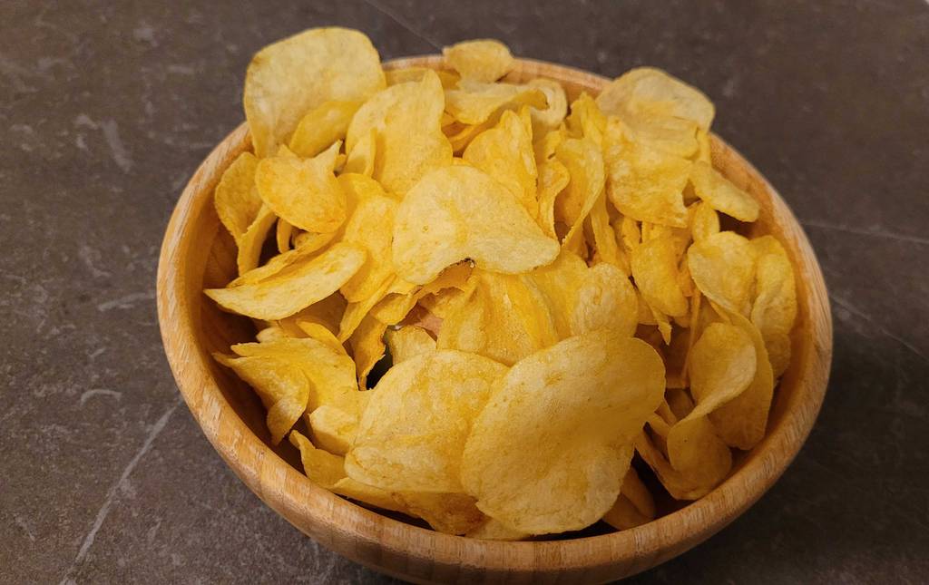Getestete Käsechips liegen aufgetürmt in einer Holzschüssel.