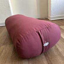 Rotes Yoga-Bolster auf dem Boden.