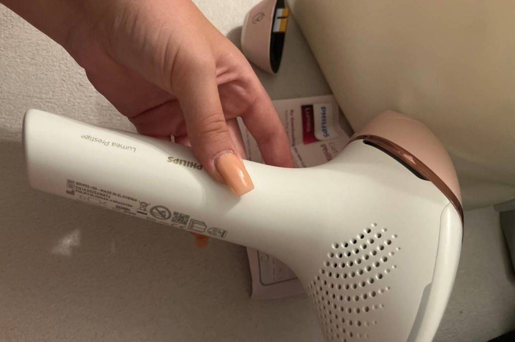 Hand hält ein getestetes IPL-Gerät der Marke Philips mit Blick auf die Belüftungsaussparungen in die Kamera.