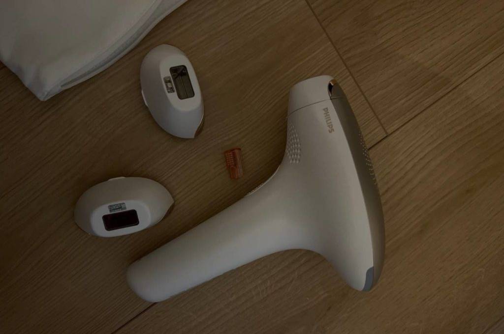 IPL-Geräte-Test: weißes Philips Modell befindet sich neben zwei Aufsätzen auf einem hellbraunen Boden.
