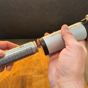 Eine Hand befestigt eine Butangasflasche am Lurch-10890-Butangasbrenner