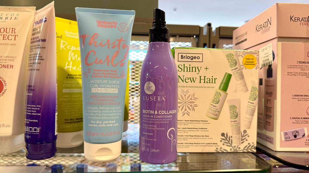 Ein lilafarbener Pumpspender inklusive getestetem Leave-in-Conditioner von Luseta steht neben weiteren Haarpflegeprodukten auf einem Verkaufsregal.