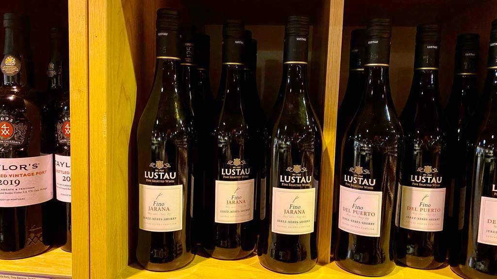 Mehrere blickdichte Flaschen mit Lustau Sherry im Test befinden sich in einem Verkaufsregal mit weiteren roten Weinen.