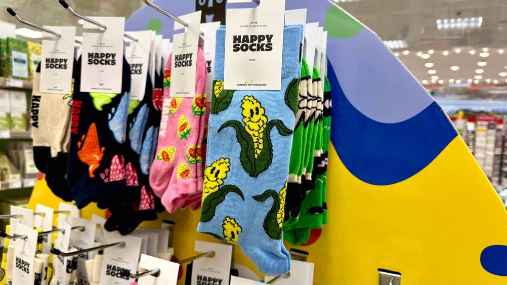Ein Paar der lustigen Socken hängen neben anderen Motiven in einem Verkaufsregal.