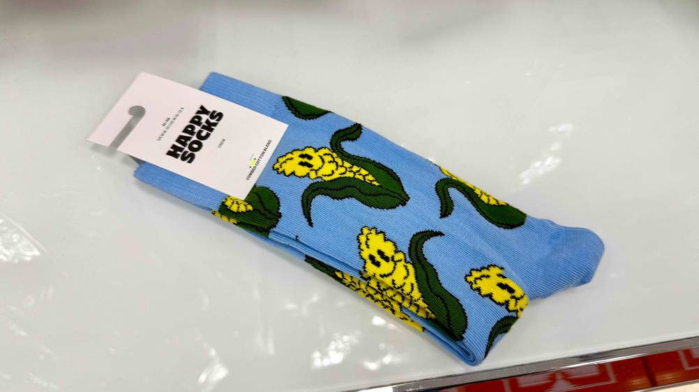 Ein Paar der lustigen Socken im Test mit Maiskolben darauf liegen auf einer hellen Fläche.