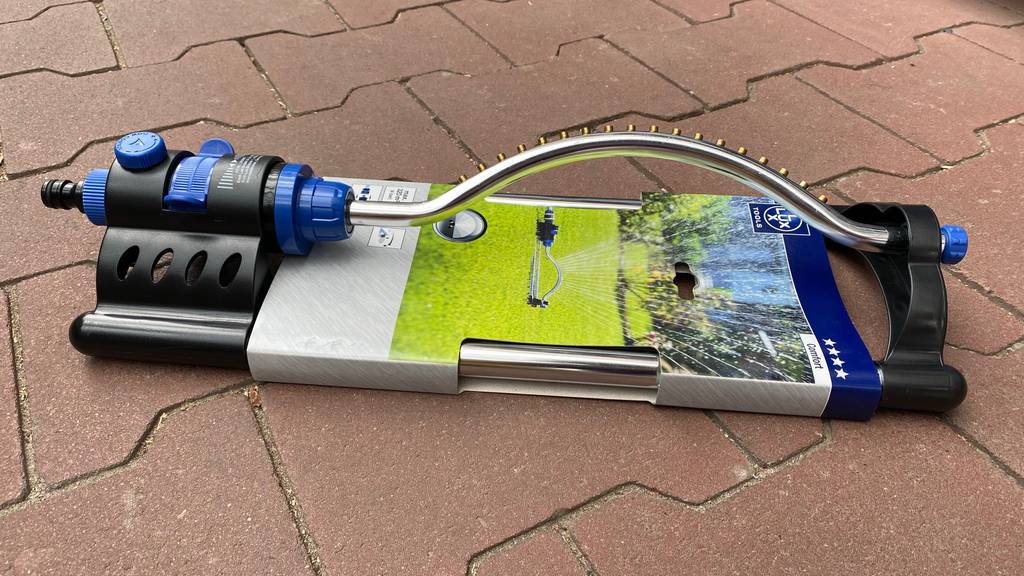 Getesteter LUX-Viereckregner inklusive Verpackung liegt auf einem Terrassenboden.