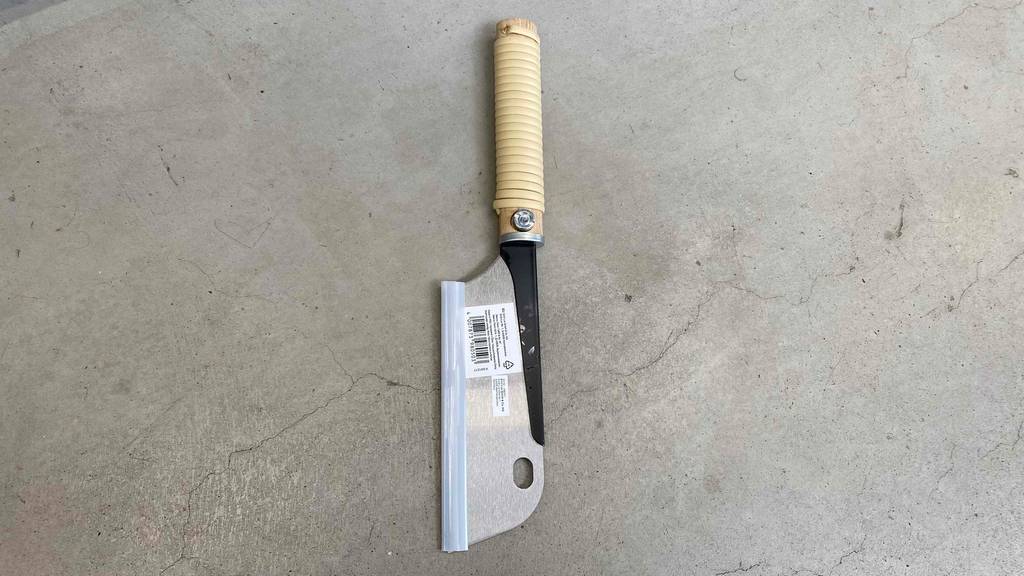 Im Test: Japansäge von Lux Tools liegt senkrecht mit Stiel nach oben auf Betonboden.