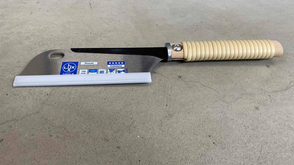 Im Test: Japansäge von Lux Tools liegt auf Betonboden.