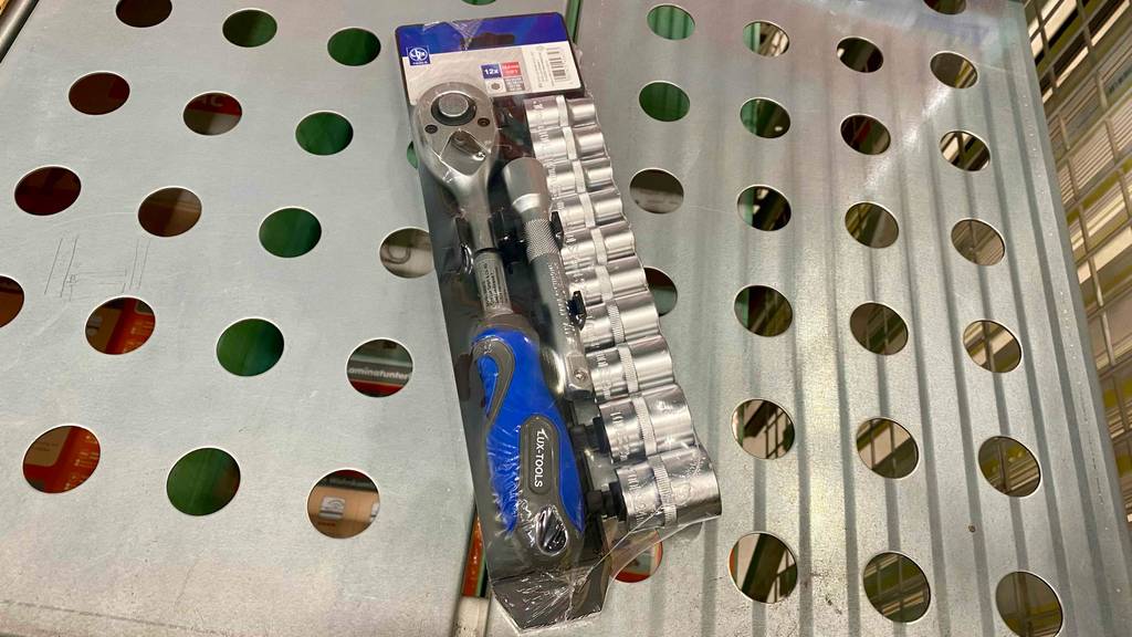 Im Test: Ein verpackter Steckschlüsselsatz liegt auf einer gelöcherten Unterlage.