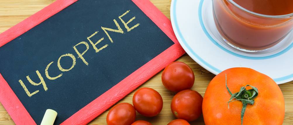 Lycopin-Kapseln-Test: Tafel mit dem Wort Lycopene, Tomaten und eine Tasse mit Tomatensaft