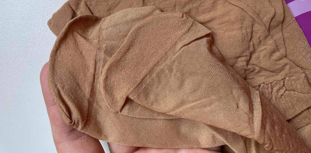 Strumpfhosen im Test: Detailansicht der verstärkten Zehenspitzen einer hautfarbenen, seidig glänzenden Feinstrumpfhose.