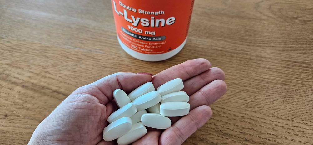 Eine Hand hält mehrere getestete Lysin-Tabletten. 