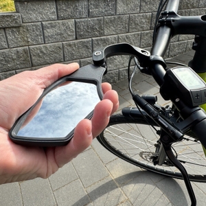 Eine Hand dreht den M-Wave-SPY-Space-Fahrradspiegel in Schwarz nach oben.