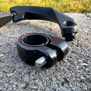 Eine Halterung liegt vor einem M-Wave-SPY-Space-Fahrradspiegel in Schwarz auf einem Stein.