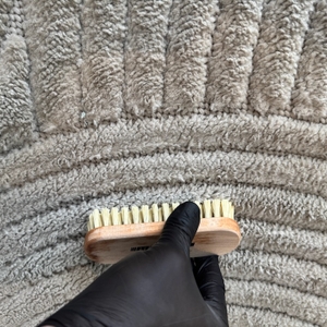 Der Teppich wird mit einer Bürste gereinigt.