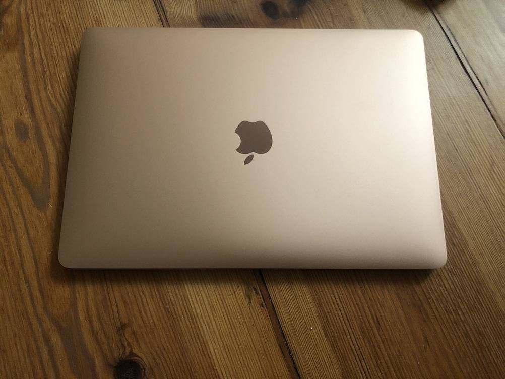 Ein getesteter MacBook liegt auf Holzboden.