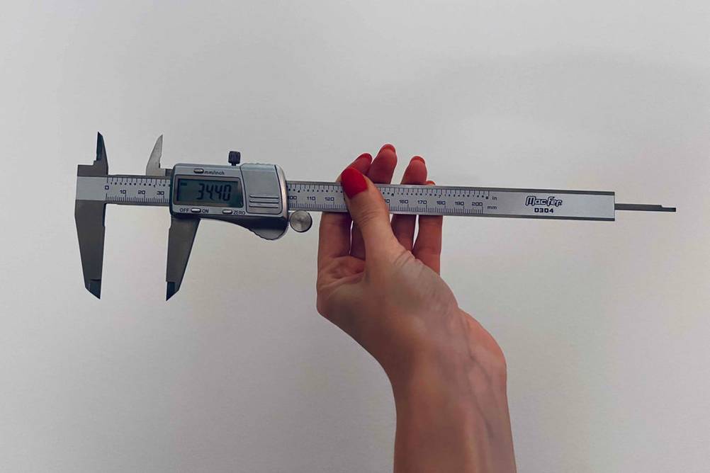Im Test: Hand hält einen digitalen Messchieber von MacFer vor einer weißen Wand.