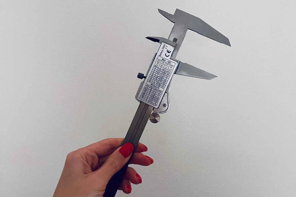 Im Test: Rückseite eines von einer Hand vor weißer Wand gehaltenen digitalen Messschiebers.