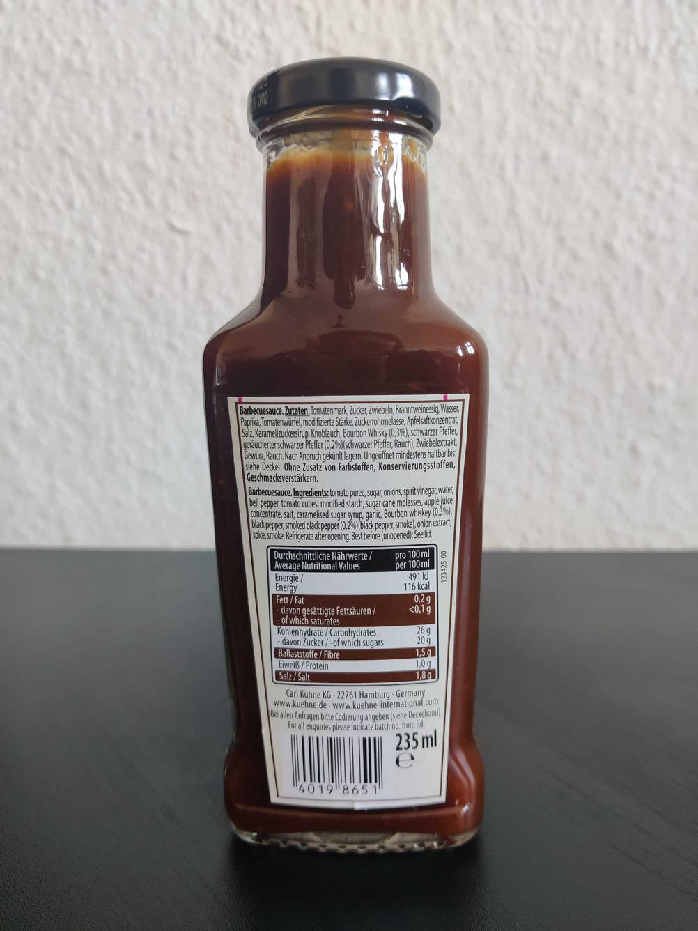 Im Test: Rückseite einer Flasche BBQ-Sauce mit der Zutatenliste vor einer hellen Wand.