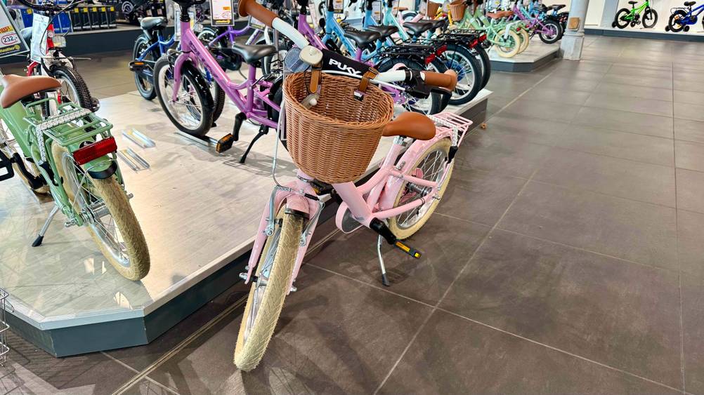 Ein Mädchenfahrrad 16 Zoll im Test von vorne mit Korb in einem Laden.