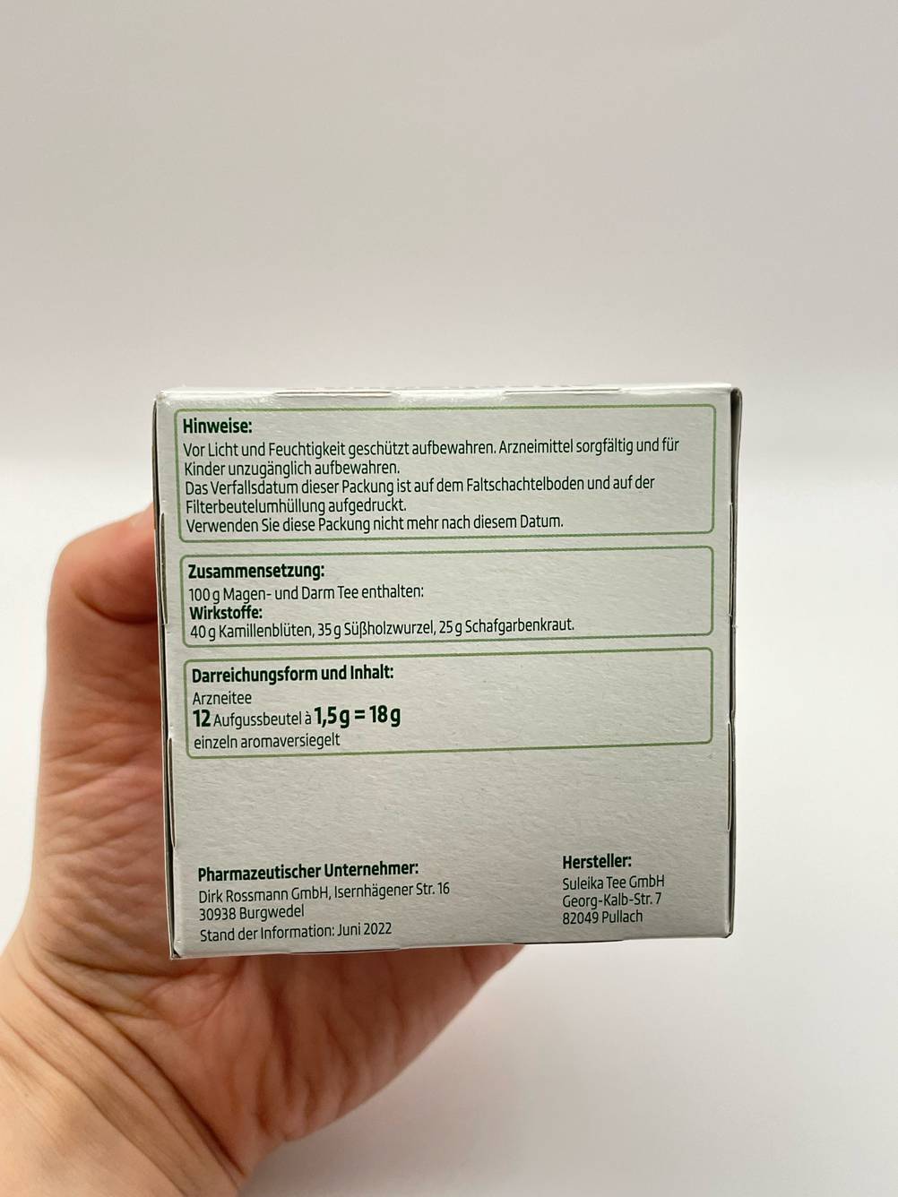 Eine Hand hält eine Seite der Verpackung hoch, darauf Informationen.
