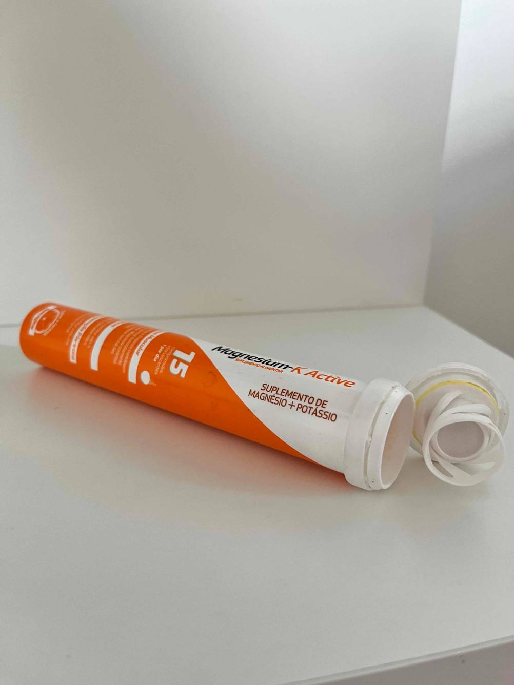 Im Test: Eine geöffnete Röhre Magnesium Brausetabletten liegt quer in weißem Regal.