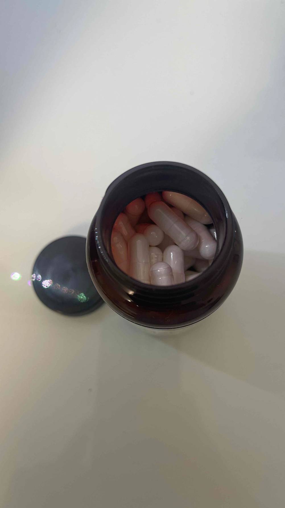 Ansicht von oben auf das Magnesium-Malat im Test, das sich in Form von Kapseln in einer lichtdichten, geöffneten Schraubdose befindet.