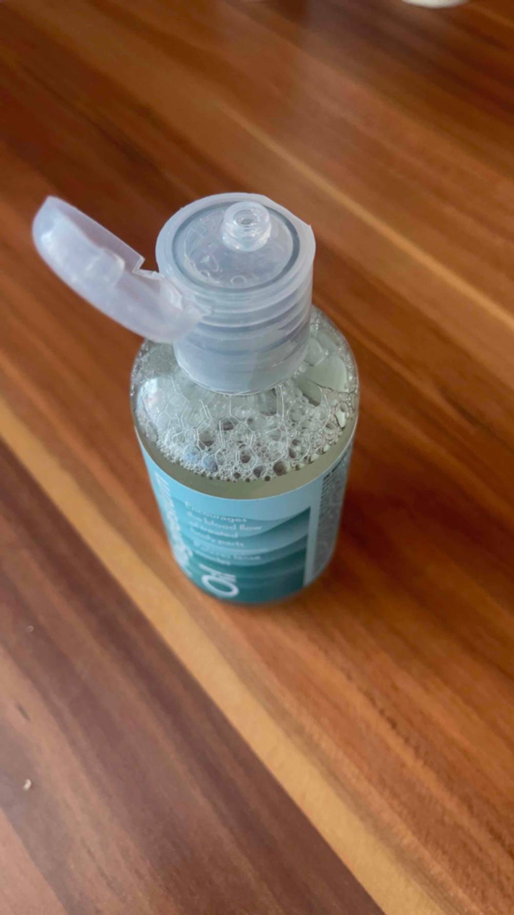 Im Test: Das Magnesiumöl befindet sich in einer geöffneten, transparenten Flasche mit Dosierverschluss auf einer Holzoberfläche.