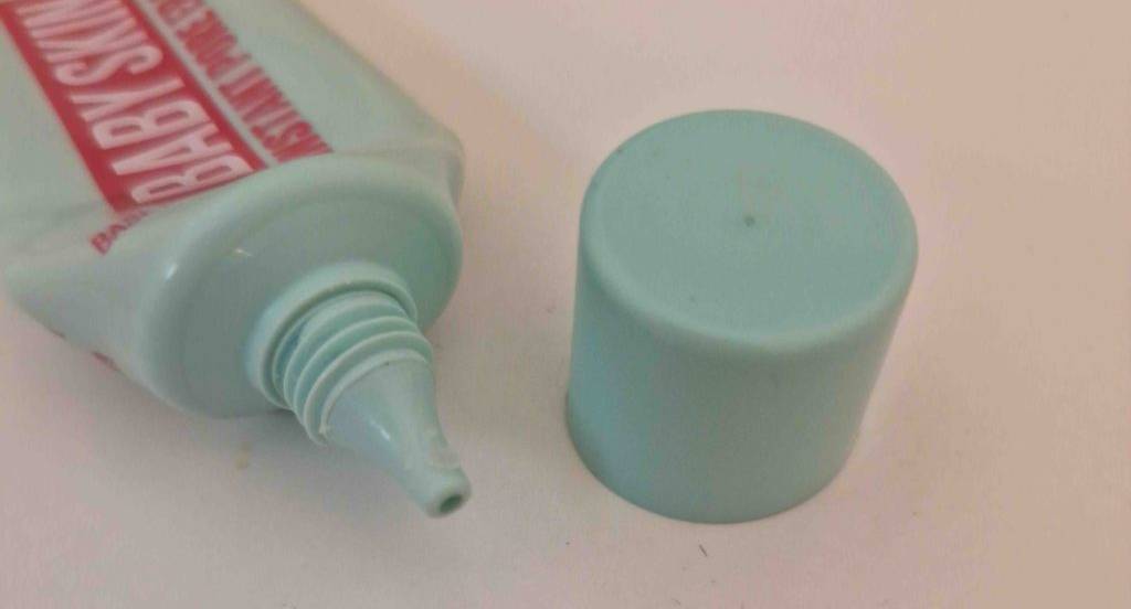 Nahaufnahme einer geöffneten grünen Tube Make-up-Primer im Test vor hellem Hintergrund.