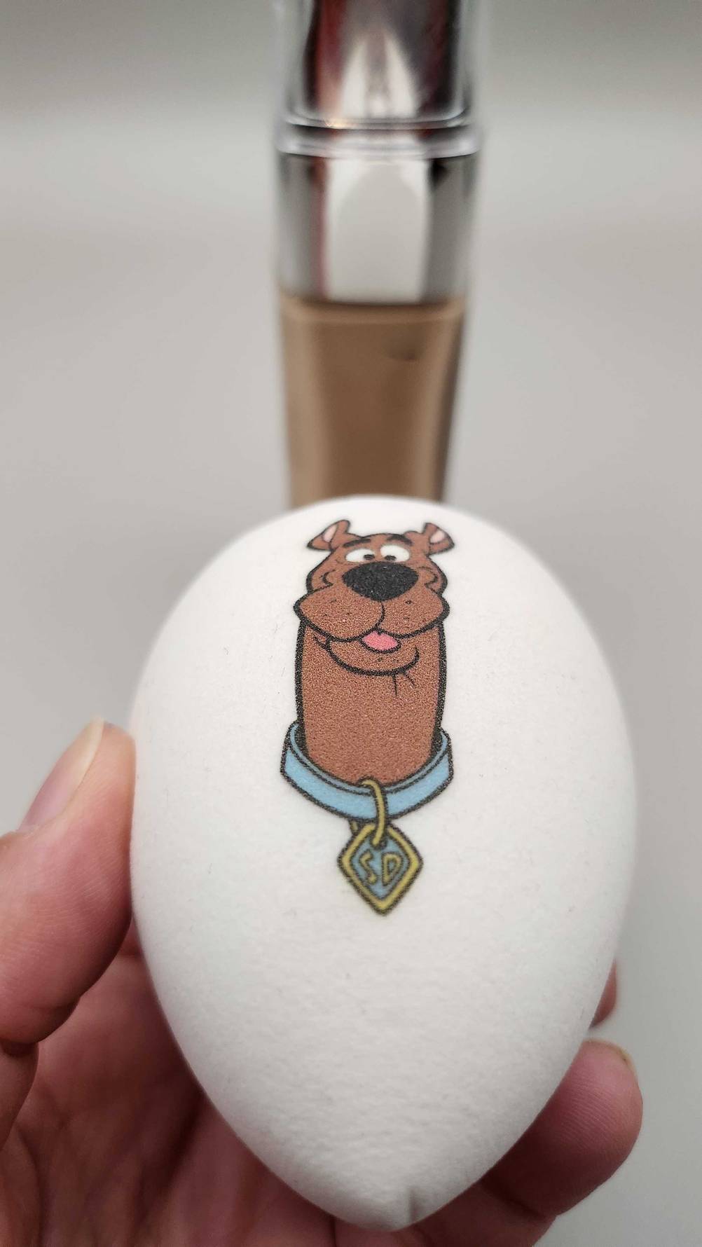 Eine Hand hält den getesteten Make-up-Schwamm mit Motiv.