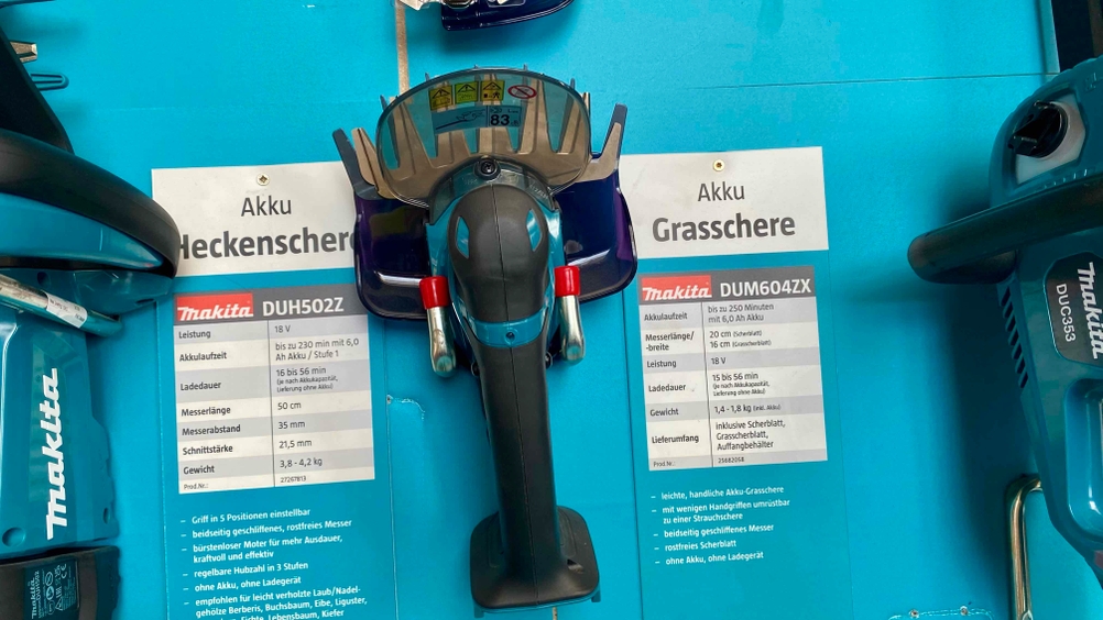 Eine getestete Akku-Grasschere von oben in einer Ausstellungsfläche mit Informationen daneben.