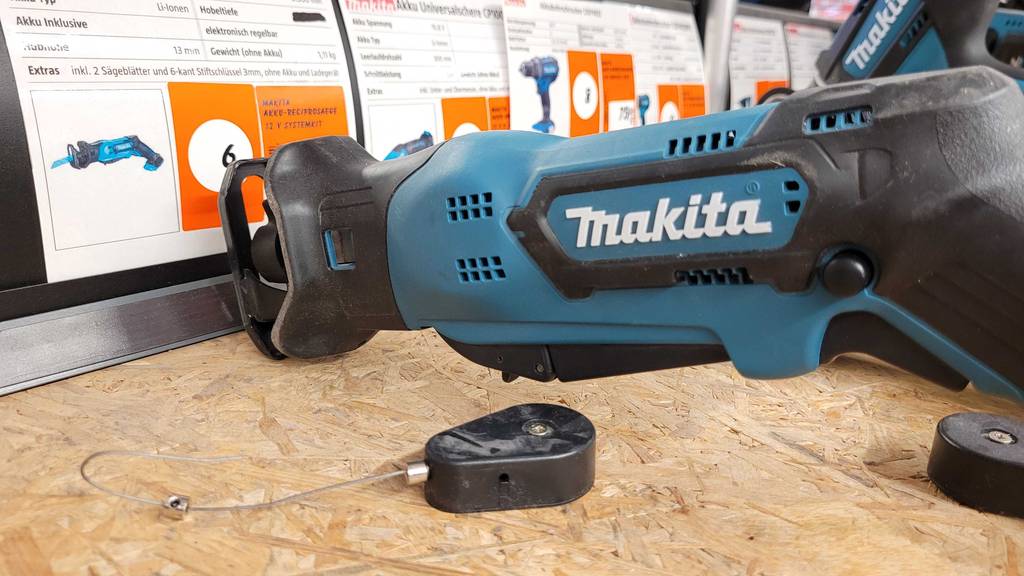 Eine Makita Säbelsäge liegt zum testen vor einem Datenplakat auf einer Korkplatte.
