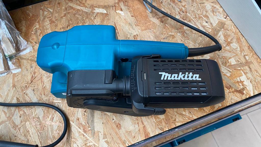 Makita-Bandschleifer-Test: Bandschleifer liegt auf Pressspanplatte.