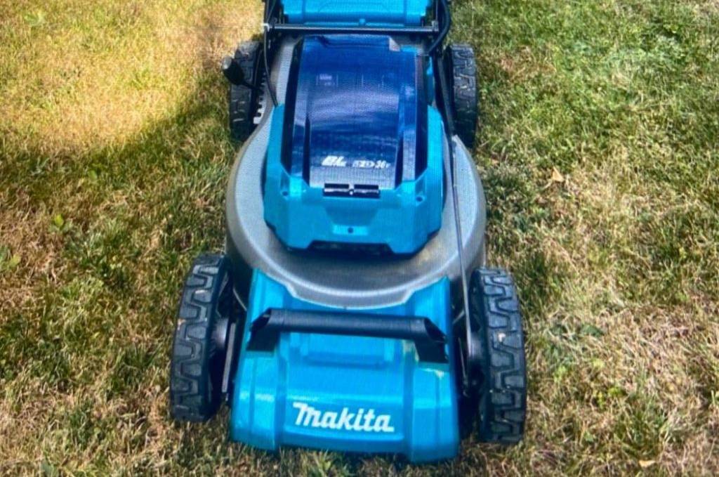 Akku-Rasenmäher im Test: Vorderansicht eines blauen Modells von Makita inklusive Auffangbeutel und höhenverstellbarem Griff auf Rasen.