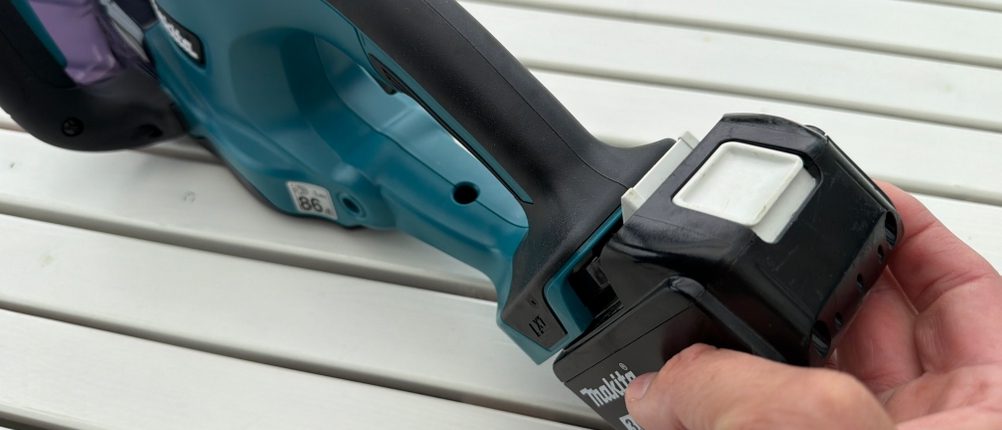 Eine Hand schiebt einen Akku auf die Makita DUH507Z