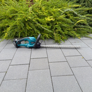 Die Makita DUH507Z liegt auf einem gepflasterten Boden