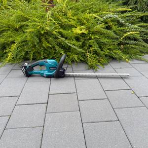 Die Makita DUH507Z liegt auf einem gepflasterten Boden