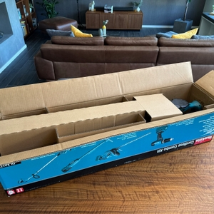 Der geöffnete Karton der Makita DUH523Z steht auf einem Tisch.