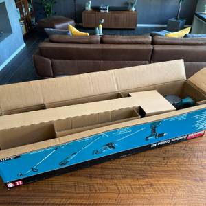 Der geöffnete Karton der Makita DUH523Z steht auf einem Tisch.