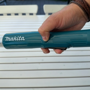 Eine Hand drückt auf die Sicherung der Makita DUN461WZ.