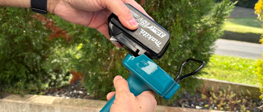 Eine Hand steckt den Akku an die Makita DUN461WZ.