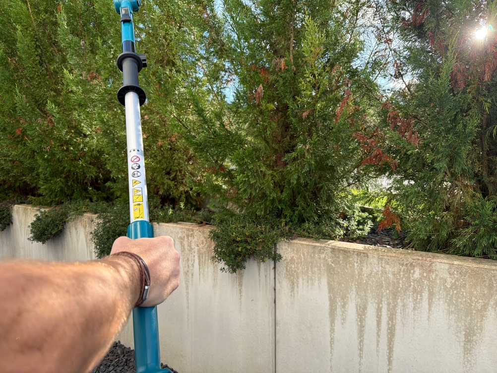 Eine Hand hält die Makita DUN461WZ beim Schneiden fest.