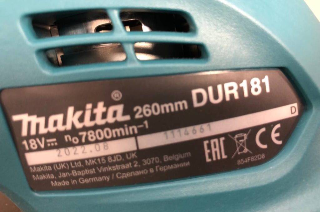 Detailansicht der Lüftungsaussparungen und des Typenschilds eines blauen Makita Akku-Rasentrimmers im Test.