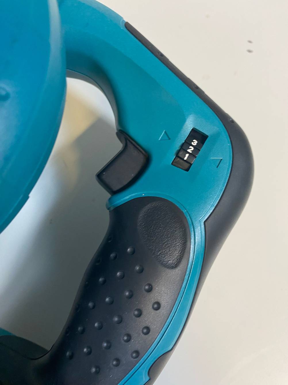 Detailansicht des Einstellungsrädchens und der Betriebstaste eines getesteten Makita-Laubbläsers.