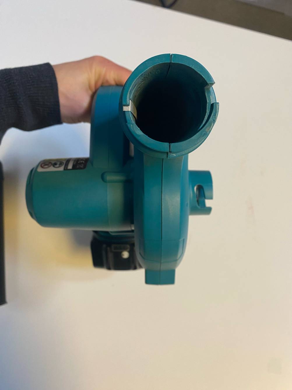 Makita-Laubbläser im Test: Eine Hand hält ein Gerät mit Blick in die Blaseinheit.