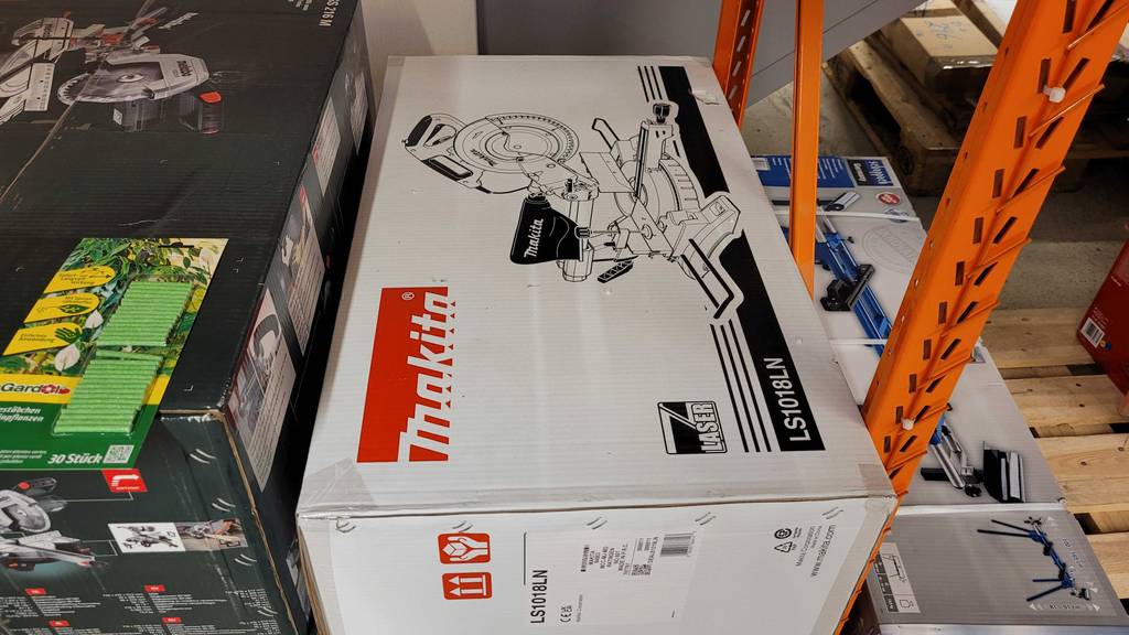 Eine Tisch-Kapp-und-Gehrungssäge liegt in ihrer Originalverpackung zum testen in einem Regal.