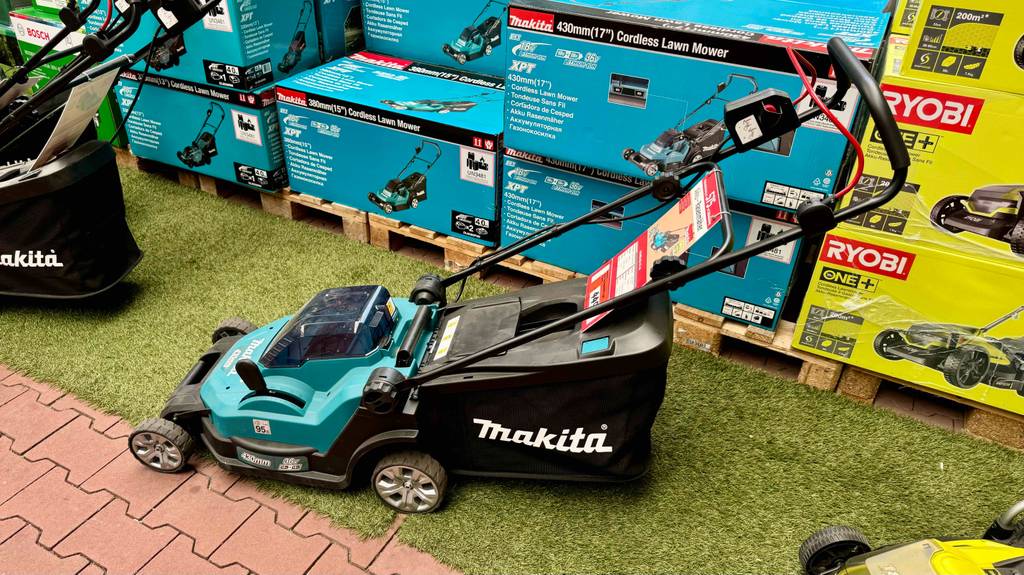 Makita Rasenmäher-Test: Seitenansicht eines Geräts, das vor einigen anderen in Verpackungskartons steht.