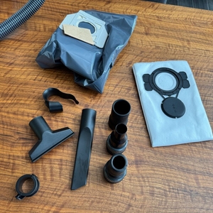 Das Zubehör des Makita VC2512L liegt auf einem Tisch