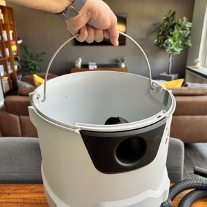 Eine Hand hält den Griff am Behälter des Makita VC2512L fest