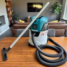 Der Makita VC2512L steht zusammen mit der Bodendüse auf einem Tisch